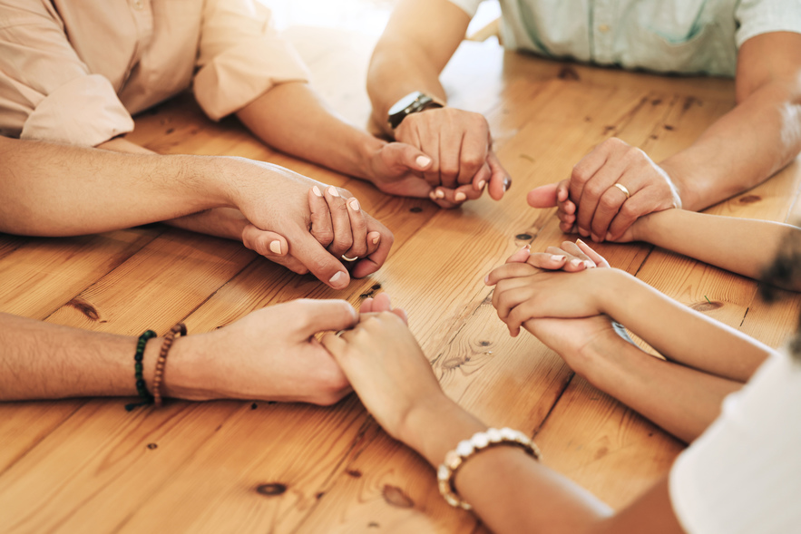 People holding hands around a table
